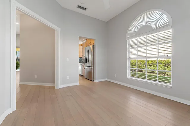 an empty room with wooden floor chandelier and windows