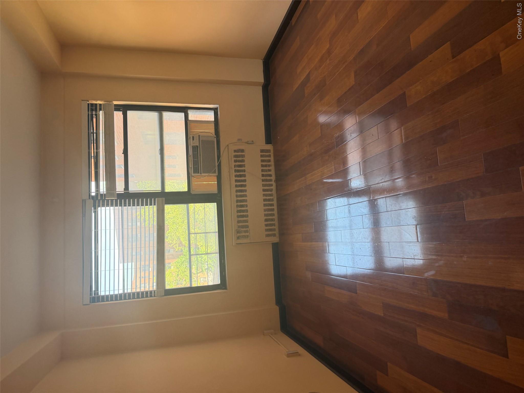 99-32 66th Road, Unit 3AA Queens, NY 11374 - Photo 7 of 9 an empty room with wooden floor and windows