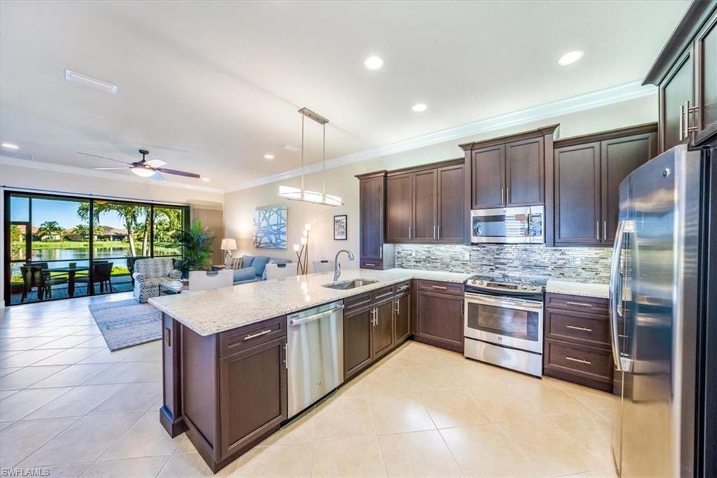 13474 Sumter Lane Naples, FL 34109 - Photo 12 of 25 a kitchen with stainless steel appliances granite countertop a sink stove and refrigerator