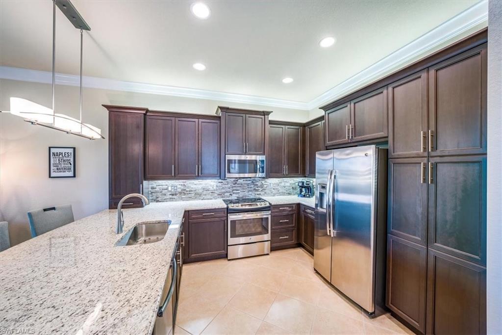 13474 Sumter Lane Naples, FL 34109 - Photo 14 of 25 a kitchen with kitchen island a counter top space cabinets and stainless steel appliances