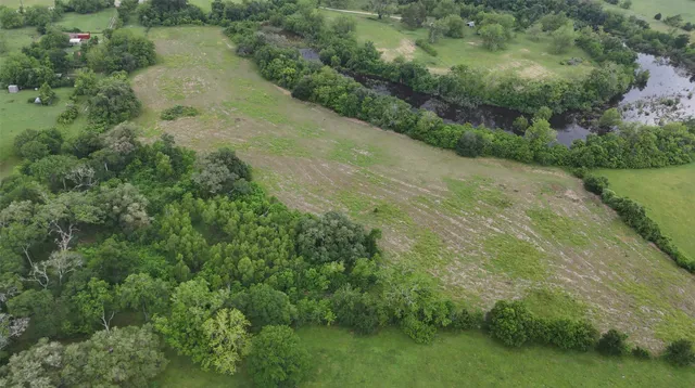 an aerial view of residential houses with outdoor space and trees