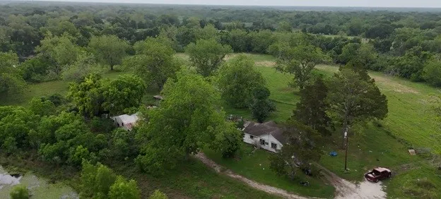 an aerial view of residential houses with outdoor space and trees
