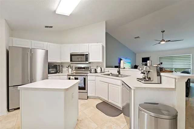a kitchen with a sink a stove a refrigerator and white cabinets