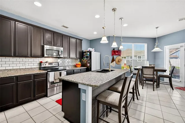 a kitchen with stainless steel appliances granite countertop a stove top oven a sink dishwasher and a refrigerator