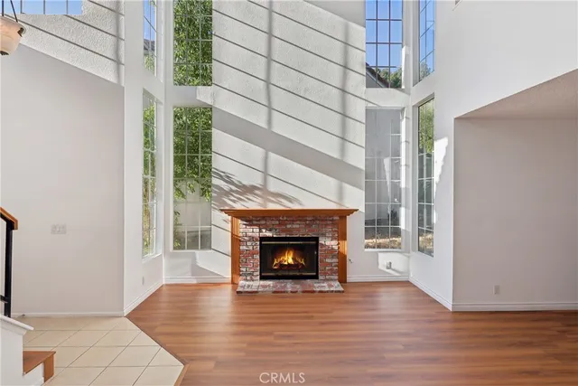a view of an empty room with wooden floor fireplace and a window
