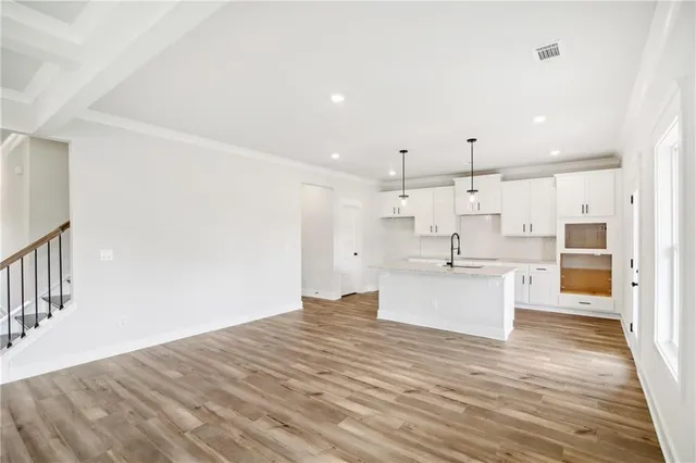 a large white kitchen with kitchen island a sink wooden floor and view living room