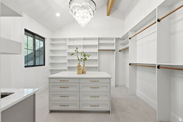 3027 Homestead Road Park City, UT 84098 - Photo 30 of 62 Custom closet system featuring extensive shelving, hanging rods, central island with drawers, vaulted ceiling, and a prominent chandelier