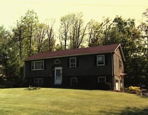 a view of house with yard and trees in the background