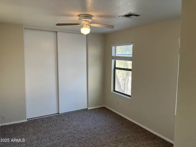 an empty room with window ceiling fan and hardwood floor