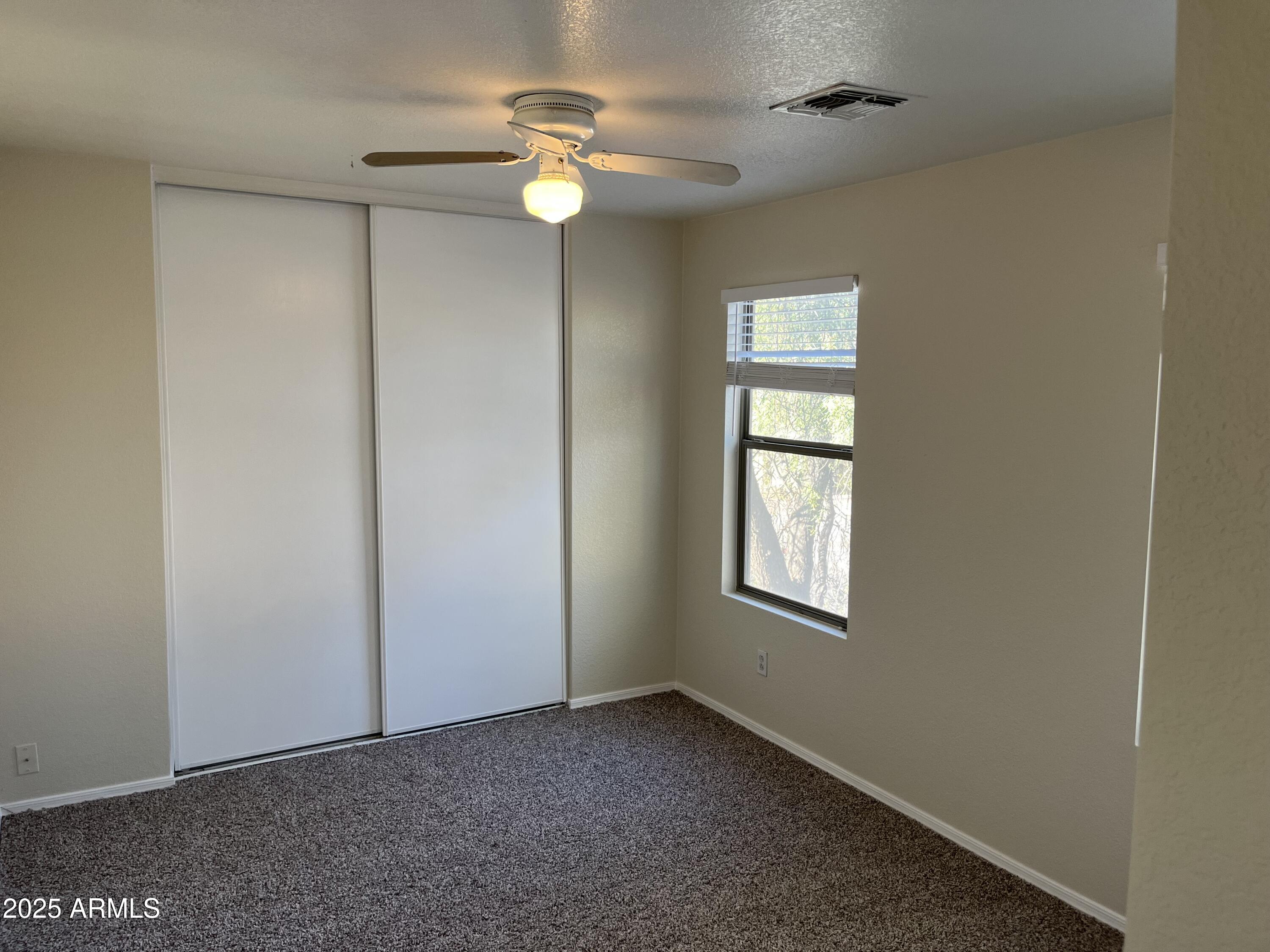 9441 West Jamestown Road Phoenix, AZ 85037 - Photo 11 of 12 an empty room with window ceiling fan and hardwood floor