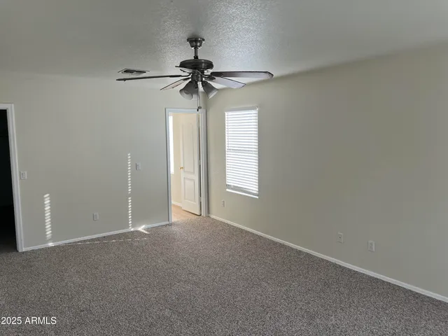 an empty room with a window and a fan