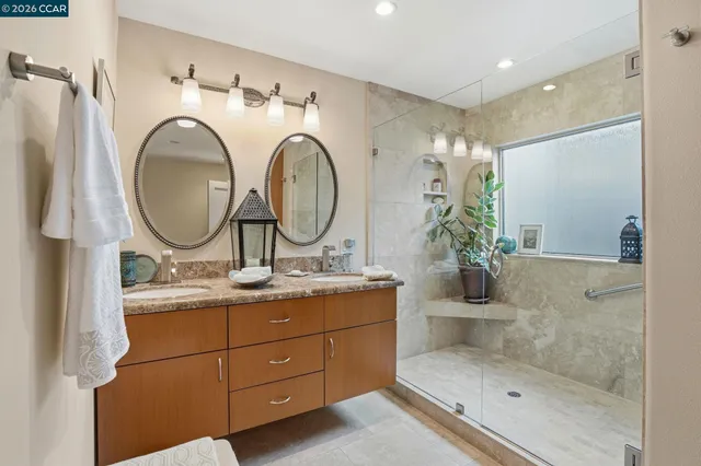 a bathroom with a granite countertop sink a mirror and shower