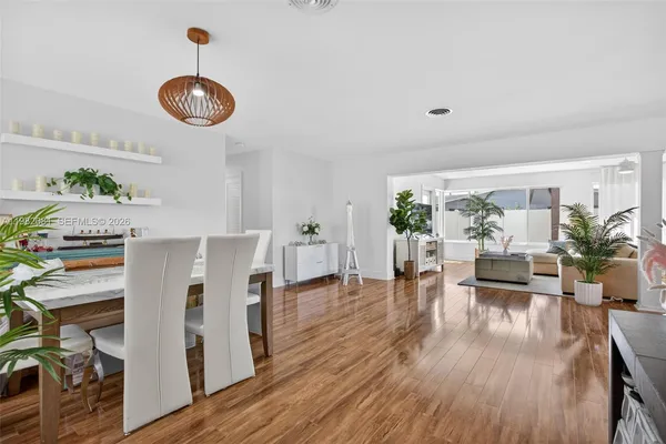 a view of a dining room and livingroom with furniture wooden floor a chandelier