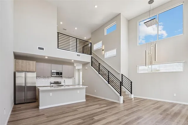 a view of kitchen with stainless steel appliances wooden floor and living room