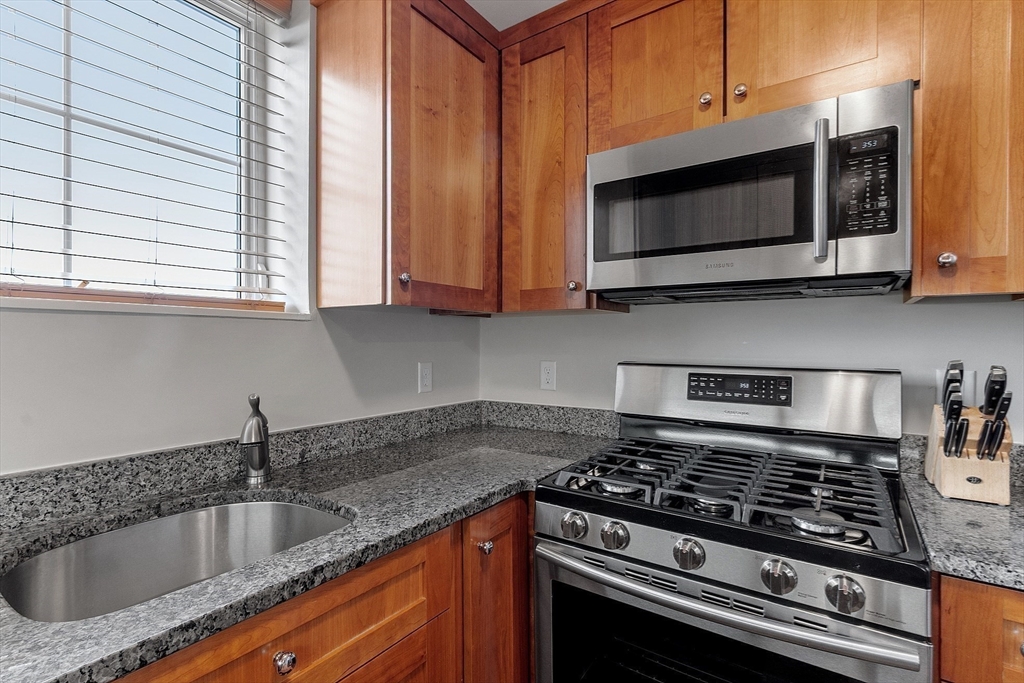 38 Village Road, Unit 602 Middleton, MA 01949 - Photo 8 of 42 a kitchen with stainless steel appliances granite countertop a sink stove and microwave