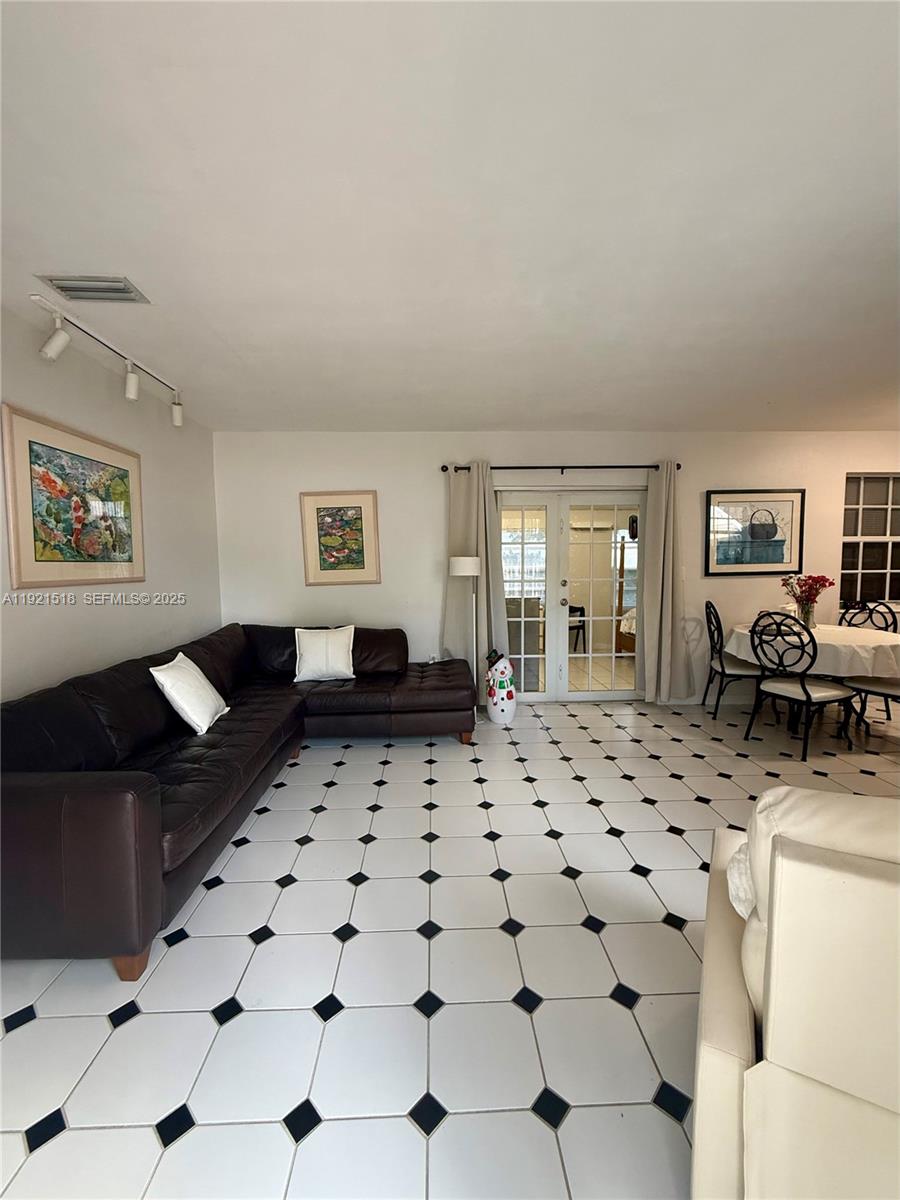 8070 Northwest 176th Street Hialeah, FL 33015 - Photo 5 of 26 a living room with furniture a flat screen tv and a refrigerator