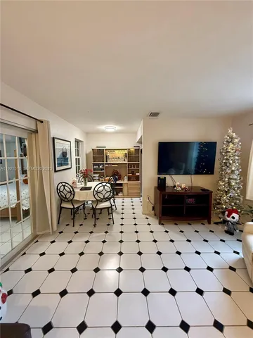 a living room with furniture a flat screen tv and a refrigerator