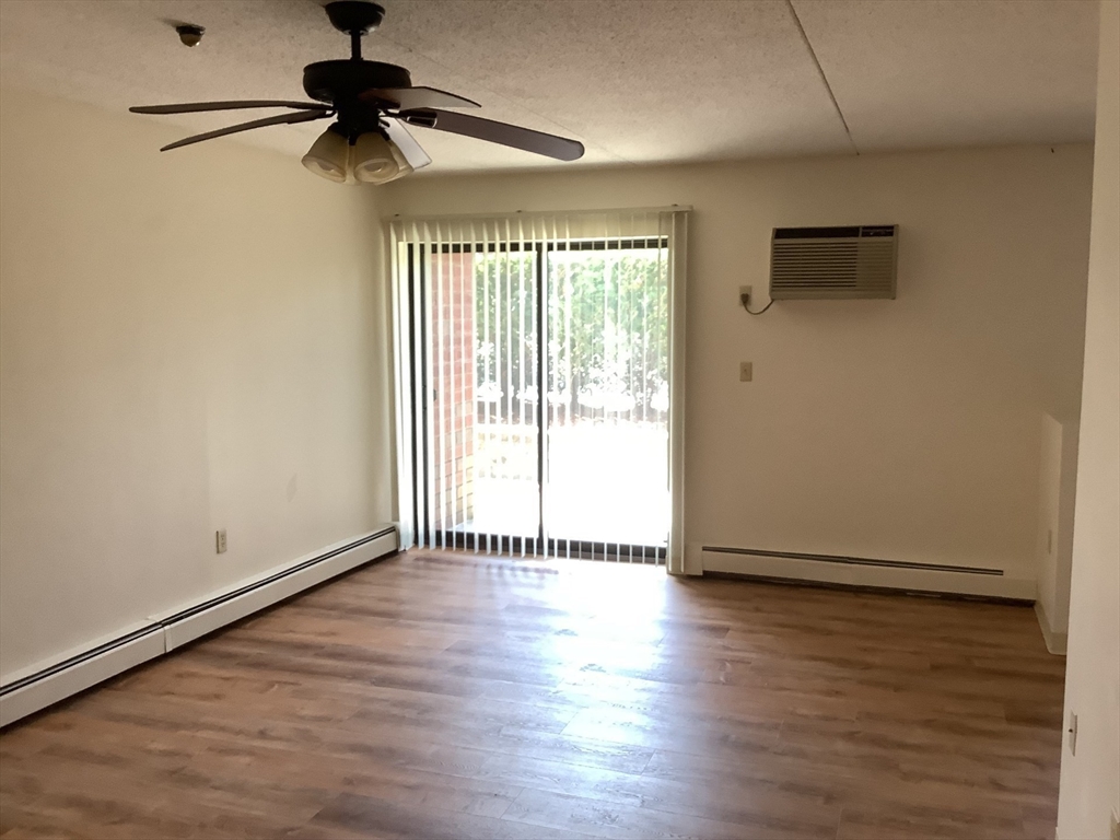 50 Cambridge Road, Unit 110 Woburn, MA 01801 - Photo 3 of 8 a view of an empty room with wooden floor and a window