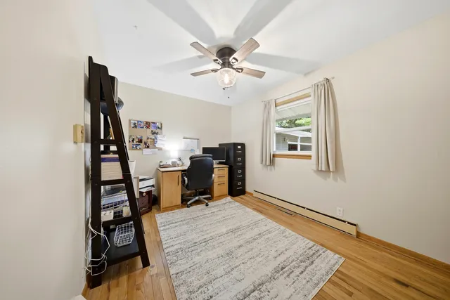 a view of a workspace with wooden floor and a ceiling fan