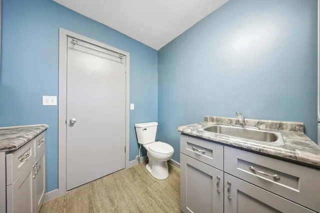 a bathroom with a granite countertop toilet and a sink