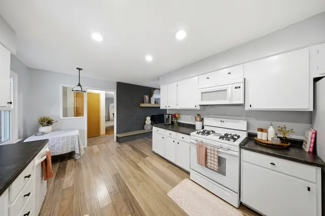 a kitchen with stainless steel appliances a stove top oven a sink dishwasher and a refrigerator with wooden floor