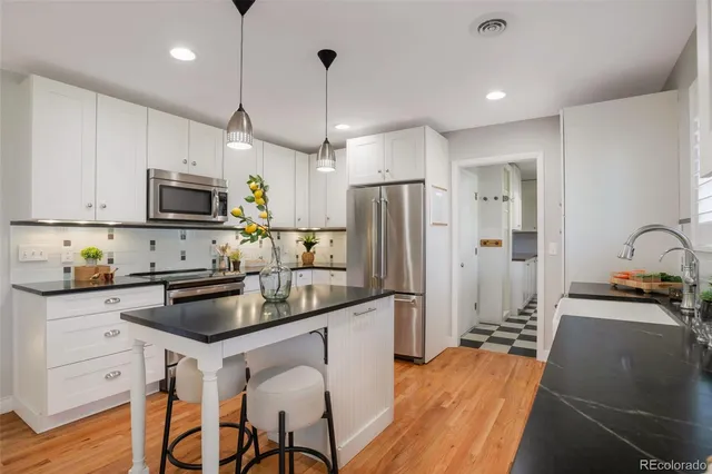 a kitchen with stainless steel appliances a stove a sink a refrigerator a microwave and wooden cabinets