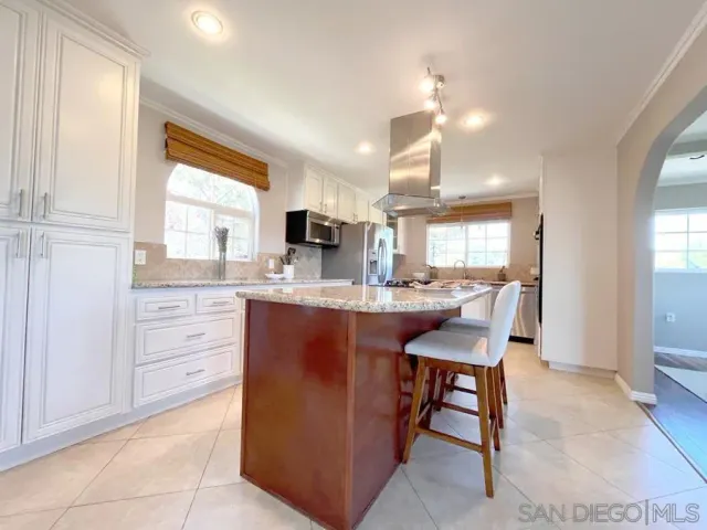 a kitchen with kitchen island granite countertop a sink cabinets and window