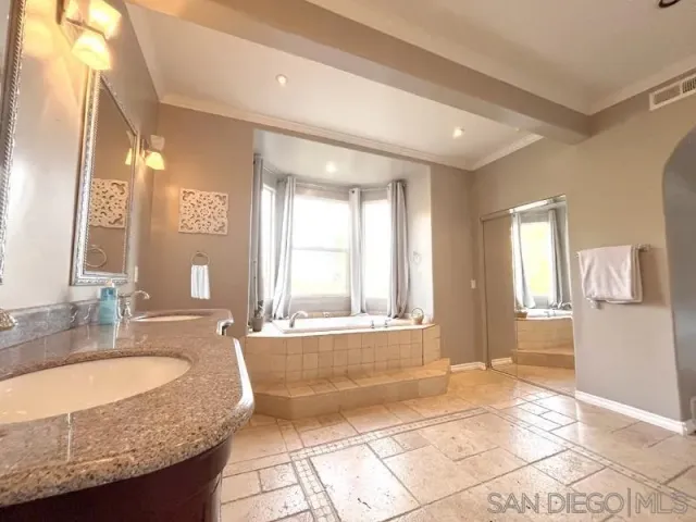 a bathroom with a granite countertop sink and a bathtub