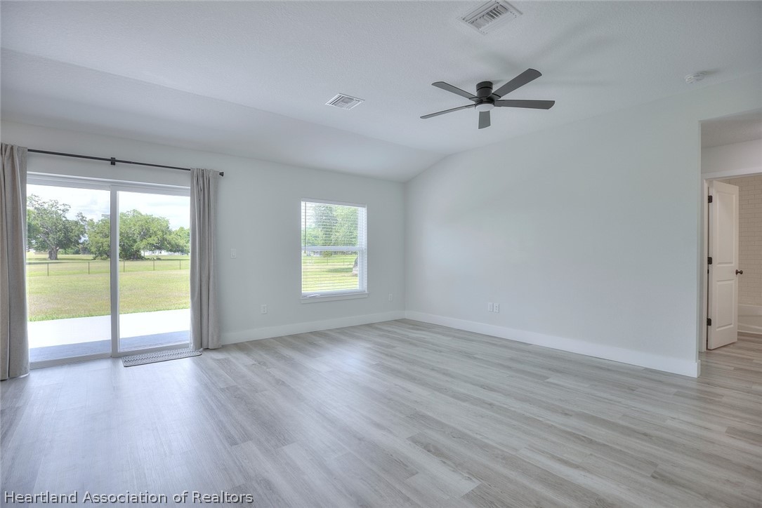 111 Vale Court Sebring, FL 33876 - Photo 6 of 40 an empty room with wooden floor and windows