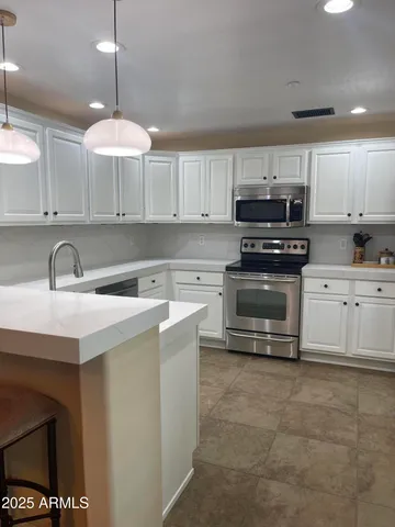 a kitchen with kitchen island a sink a stove and cabinets