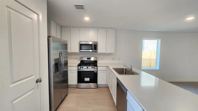a kitchen with granite countertop a refrigerator stove and sink