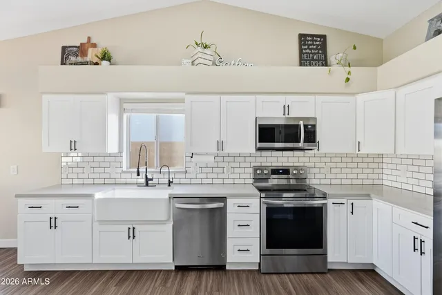 a kitchen with stainless steel appliances a sink a stove a refrigerator cabinets and dining table