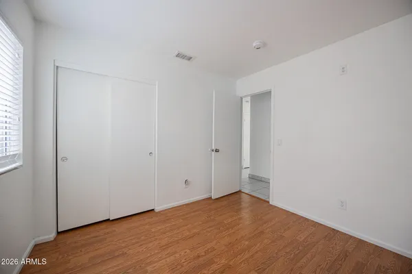 a view of empty room with wooden floor and fan