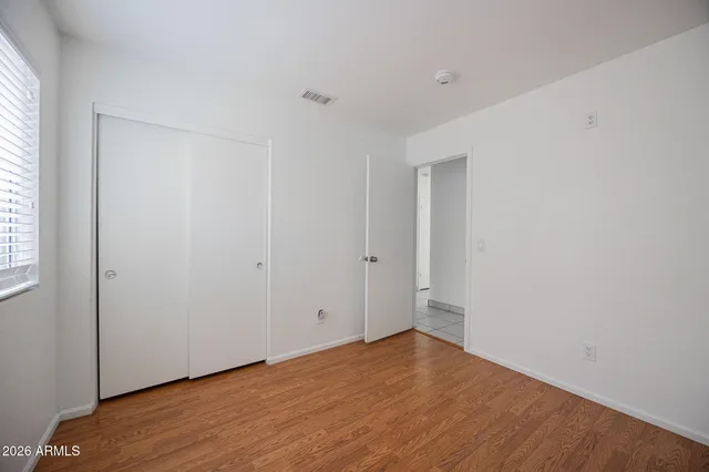 a view of an empty room with wooden floor and a window