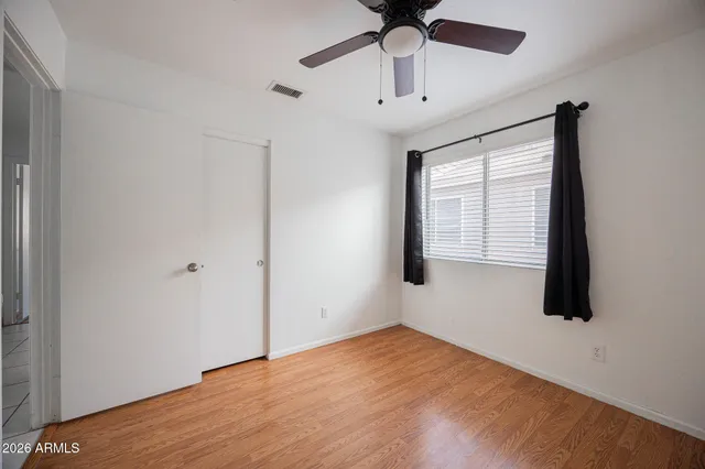 an empty room with a window and a ceiling fan
