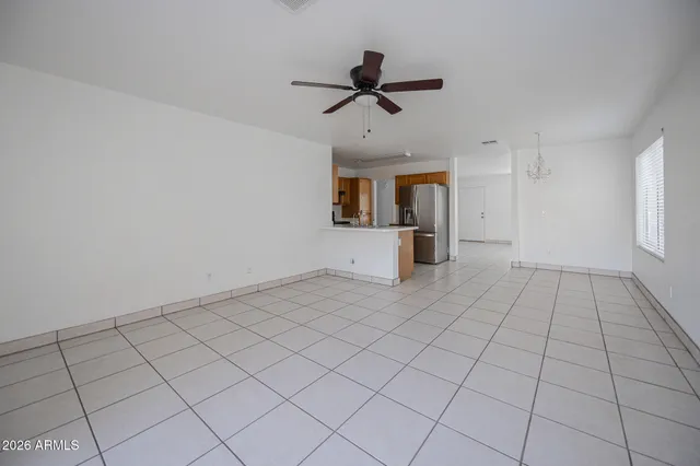 a view of an empty room and chandelier fan