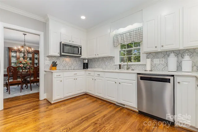 a kitchen with stainless steel appliances granite countertop a stove a sink and white cabinets