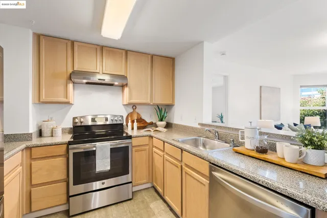 a kitchen with stainless steel appliances a stove a sink and cabinets