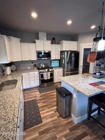a kitchen with stainless steel appliances kitchen island granite countertop a sink stove and refrigerator