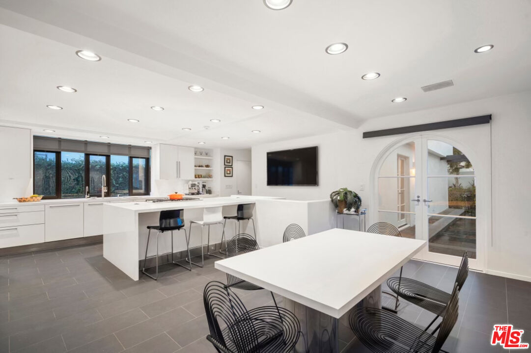 710 Walden Drive Beverly Hills, CA 90210 - Photo 8 of 20 a large white kitchen with a sink table and chairs