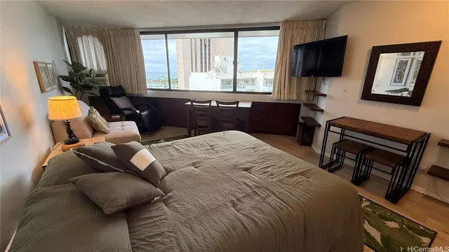 a bedroom with a bed a flat screen tv and windows