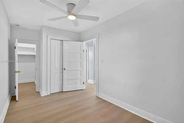 an empty room with closet and a ceiling fan