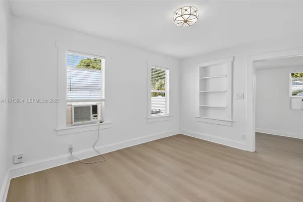 a view of an empty room with a window and wooden floor