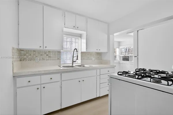 a kitchen with white cabinets a stove and a sink
