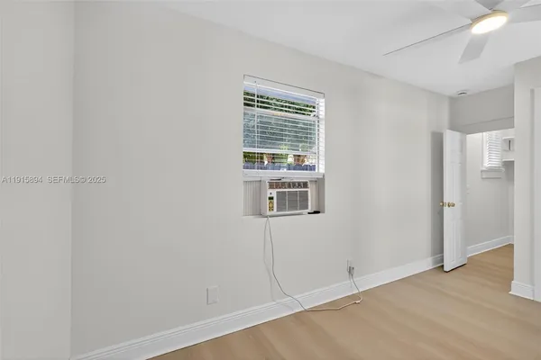 a view of an empty room with wooden floor and a window