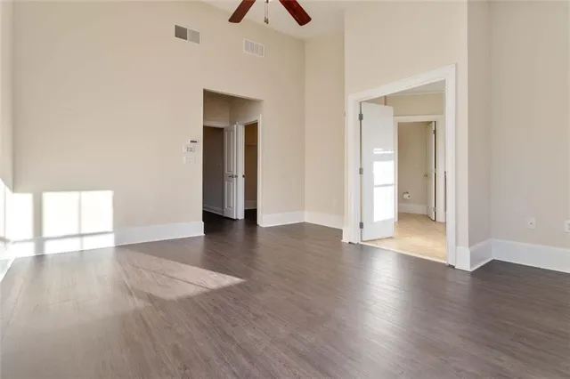 an empty room with wooden floor and a ceiling fan