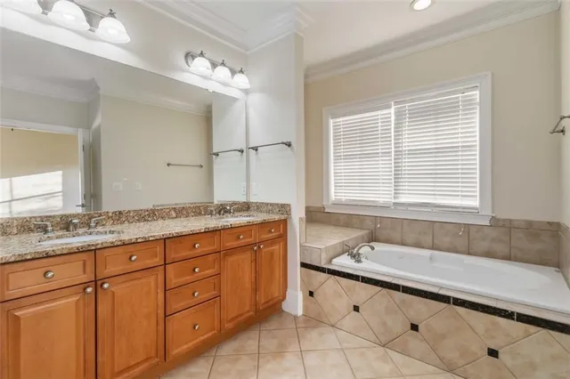 a spacious bathroom with a granite countertop double vanity sink a mirror and a bathtub
