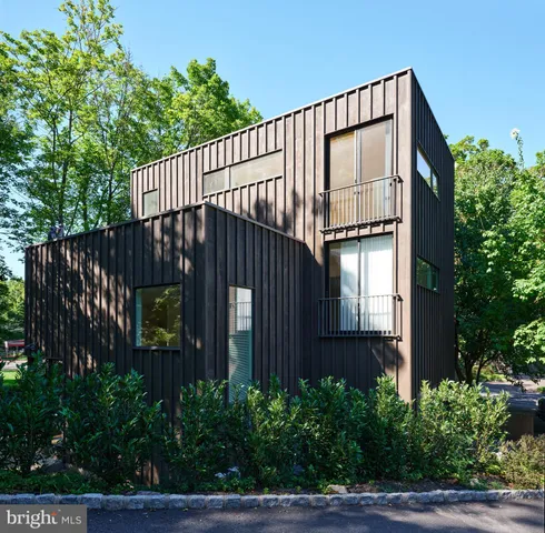 a view of a brick house with plants and wooden fence