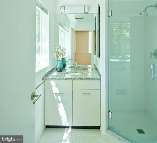 a bathroom with a granite countertop sink a mirror and a shower