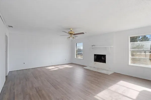 an empty room with windows and fireplace